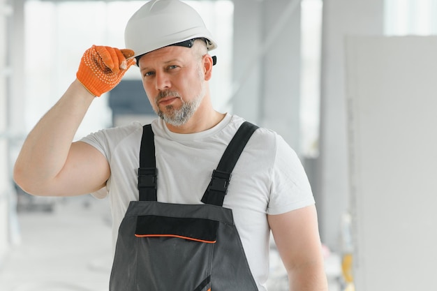 Un hombre con barba, casco y ropa de trabajo. Retrato de un trabajador en ropa de trabajo con espacio para copiar.