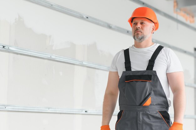 Un hombre con barba, casco y ropa de trabajo. retrato de un trabajador en  ropa de trabajo con espacio para copiar.