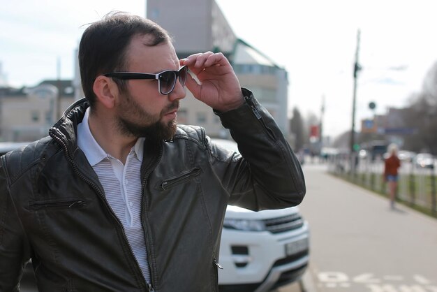 Hombre de barba con chaqueta y gafas de sol calle