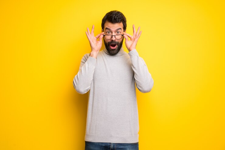 Foto hombre con barba y cuello alto con gafas y sorprendido.