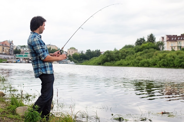 Un hombre con barba está pescando para girar en el río.