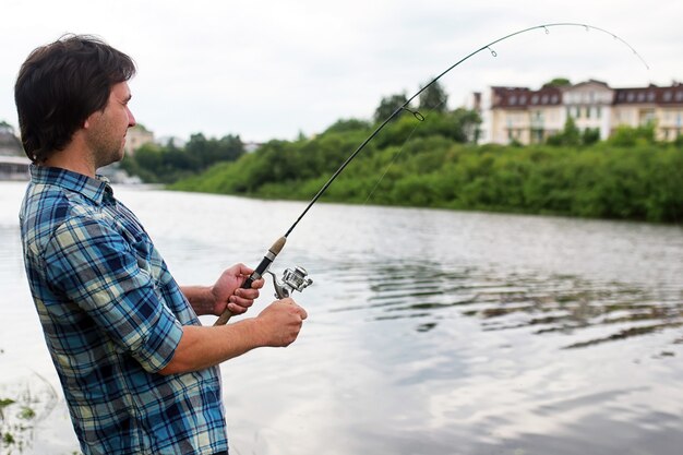 Un hombre con barba está pescando para girar en el río.