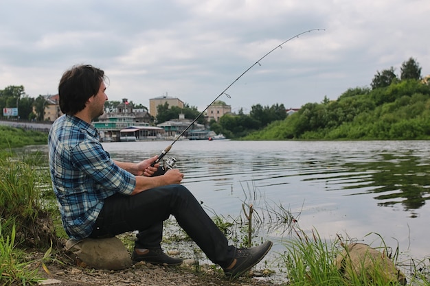 Un hombre con barba está pescando para girar en el río.