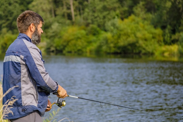 Un hombre con barba está pescando en el río.