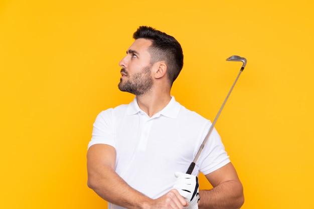 Hombre con barba jugando al golf sobre pared aislada