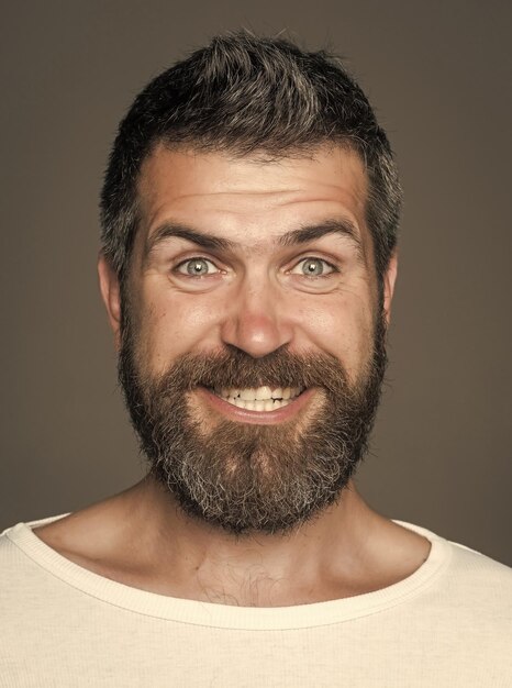 Hombre con barba larga y bigote Hipster con cara feliz Sentimiento y emociones Chico o hombre barbudo sobre fondo gris Peluquería moda y belleza