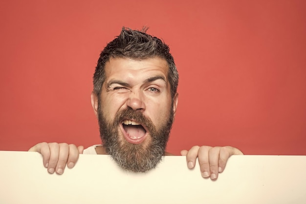 Hombre con barba larga en la cara guiñando un ojo con papel