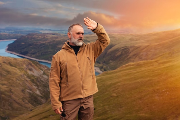 Hombre con barba llegando al destino y en la cima de la montaña al atardecer el día de otoño