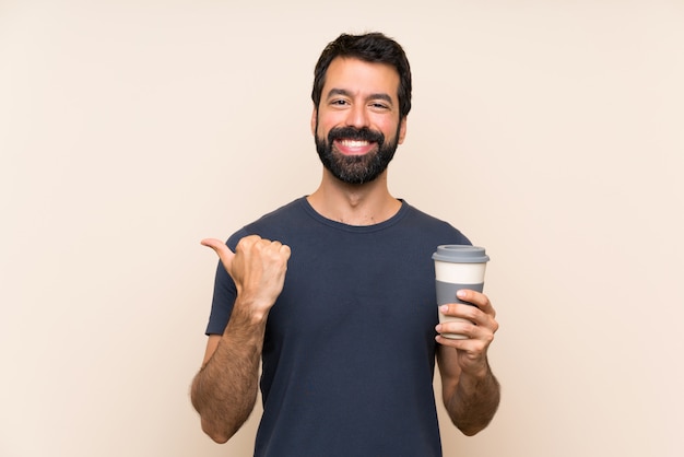 Hombre con barba sosteniendo un café apuntando hacia un lado para presentar un producto