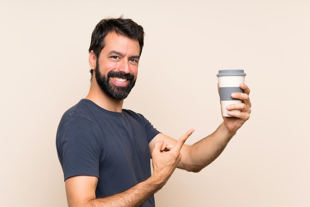 Hombre con barba sosteniendo un café y apuntando