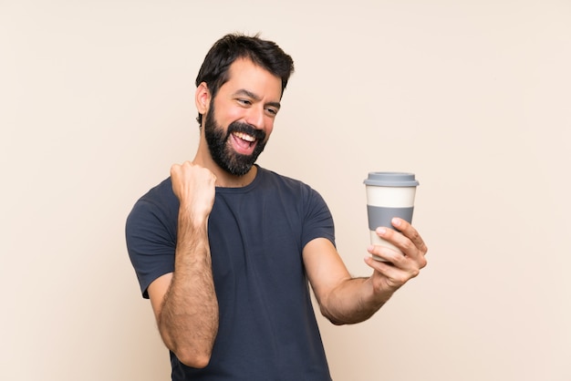 Hombre con barba sosteniendo un café celebrando una victoria