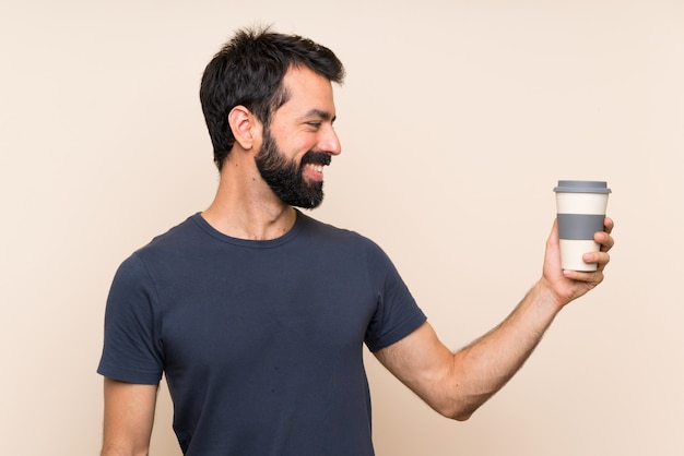 Hombre con barba sosteniendo un café con expresión feliz