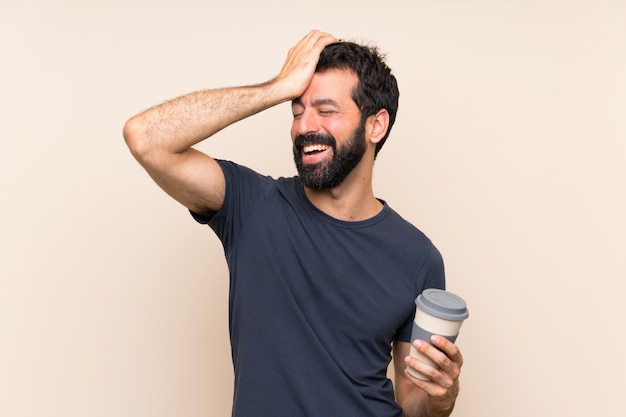 Un hombre con barba sosteniendo un café se ha dado cuenta de algo y tiene la intención de encontrar la solución.