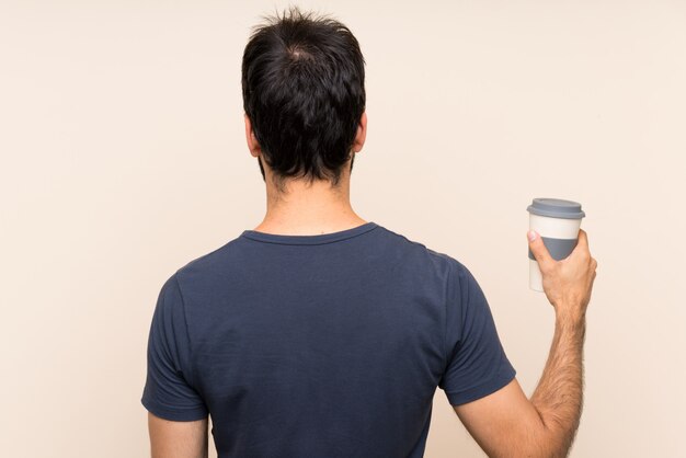 Hombre con barba sosteniendo un café en posición posterior