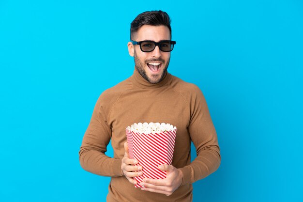 Hombre con barba sosteniendo una palomitas de maíz sobre pared aislada