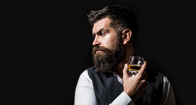 Hombre con barba sostiene brandy de vidrio