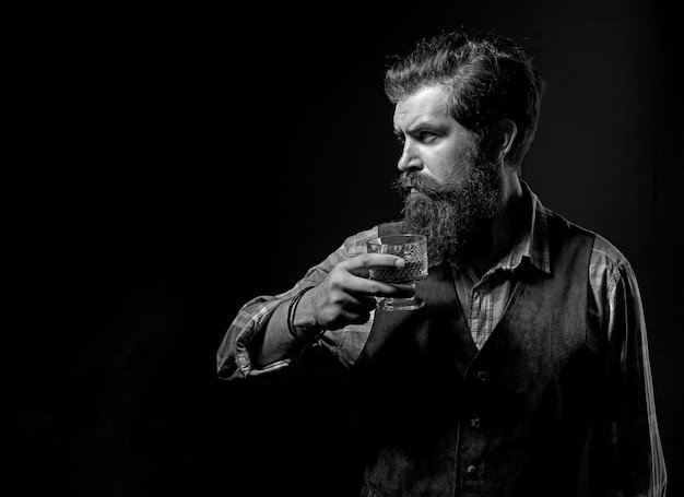 Hombre con barba sostiene una copa de brandy Bebida alcohólica de lujo El hombre barbudo alegre está bebiendo caro