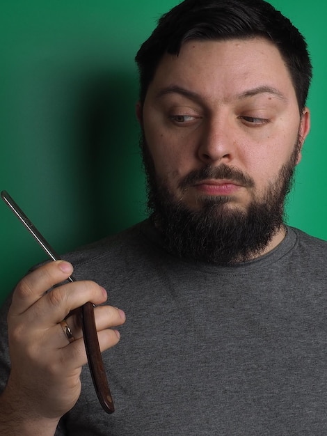 Un hombre con barba sostiene un cuchillo en la mano.