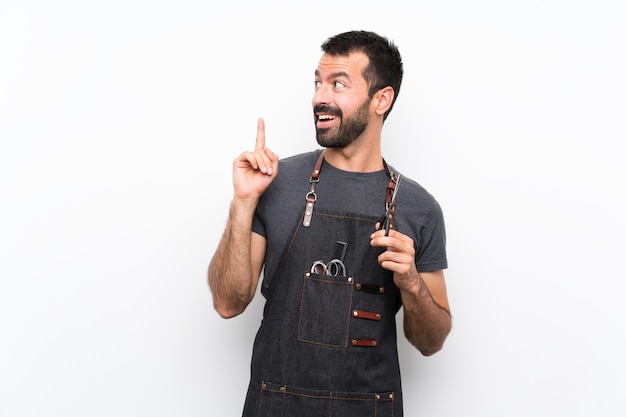 Hombre de barbero en un delantal pensando en una idea apuntando el dedo hacia arriba