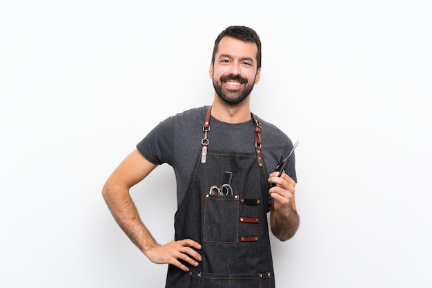 Hombre de barbero en un delantal posando con los brazos en la cadera y sonriendo