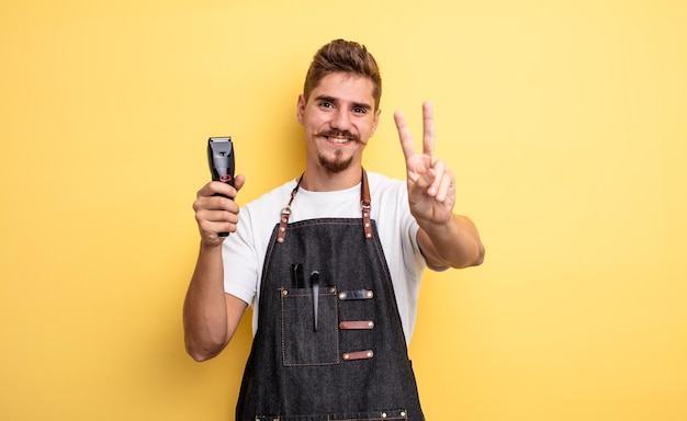 Hombre barbero hipster sonriendo y luciendo amigable, mostrando el número dos