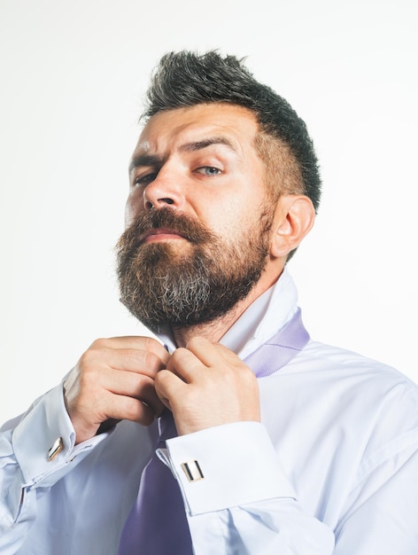 Hombre barbudo abotonándose la camisa en el cuello que se viste con ropa de mañana detalle hombre elegante recibiendo