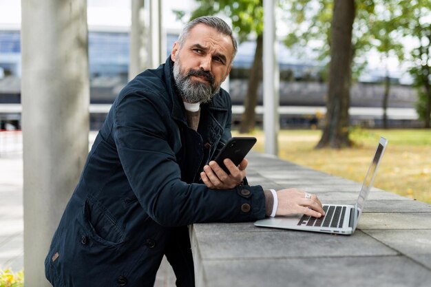 Hombre barbudo adulto que trabaja en la computadora portátil afuera