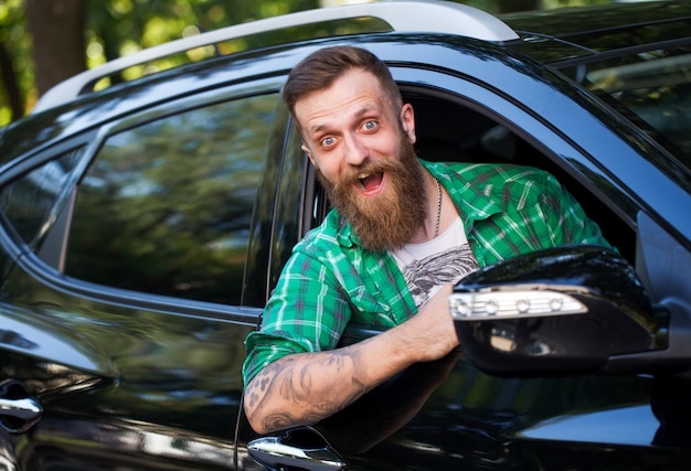 Hombre barbudo alegre en el coche.