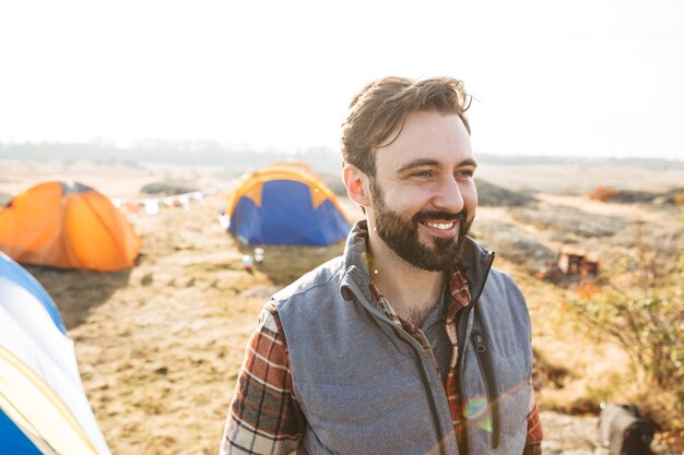 Hombre barbudo alegre guapo acampando al aire libre