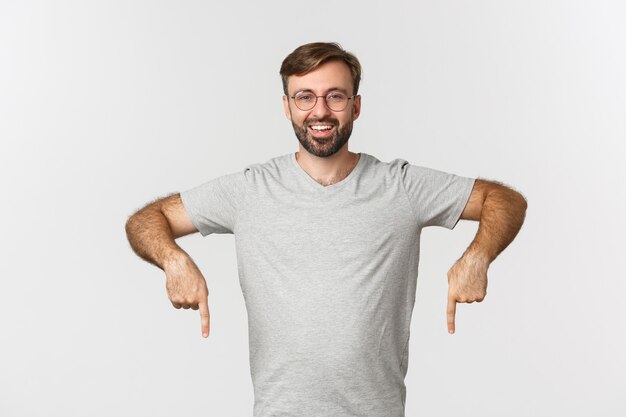 Hombre barbudo alegre sonriendo, señalando con el dedo hacia abajo