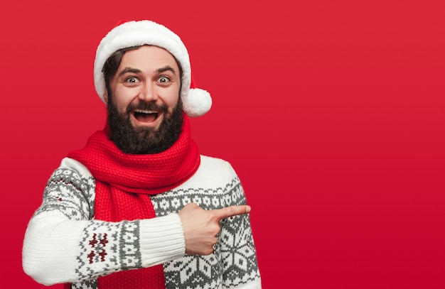 Hombre barbudo asombrado en suéter de Navidad y gorro de Papá Noel