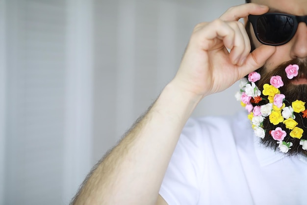 Un hombre barbudo con barba decorada para las vacaciones de primavera. Flores en la barba.