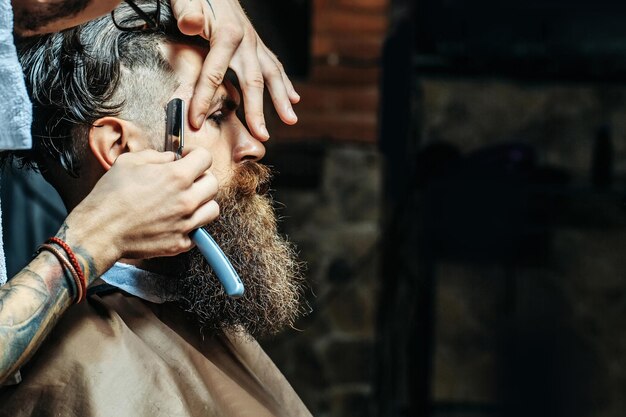 Foto hombre barbudo con barba larga para afeitarse el cabello con navaja