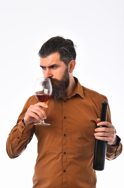 Foto hombre barbudo barba larga brutal hipster caucásico con bigote con botella de vino y vaso con bebida alcohólica tiene cara seria en camisa marrón aislado en el espacio de copia de fondo blanco