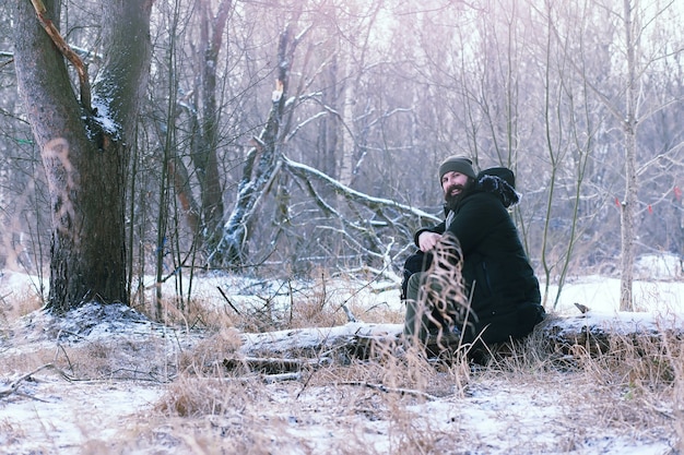 Hombre barbudo en el bosque de invierno. Atractivo joven feliz con barba caminar en el parque.