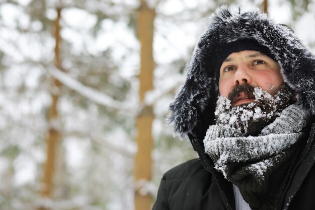 Hombre barbudo en el bosque de invierno. Atractivo joven feliz con barba caminar en el parque.