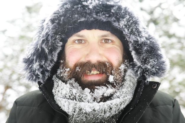 Hombre barbudo en el bosque de invierno. Atractivo joven feliz con barba caminar en el parque.