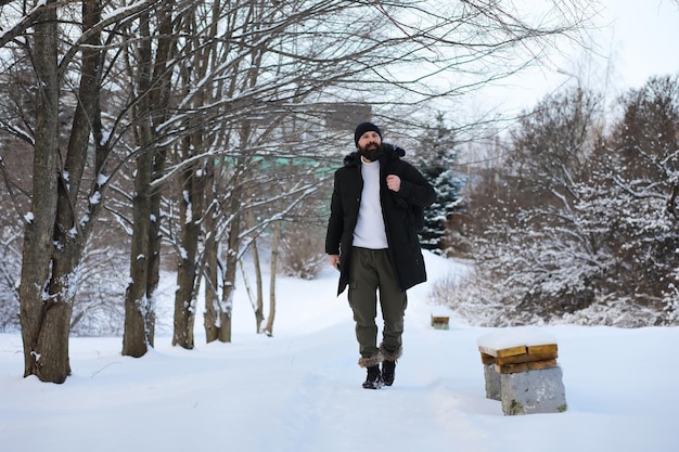 Hombre barbudo en el bosque de invierno. Atractivo joven feliz con barba caminar en el parque.