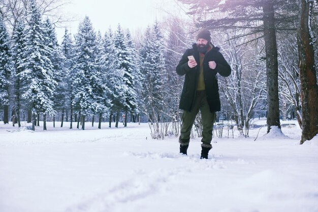 Hombre barbudo en el bosque de invierno. Atractivo joven feliz con barba caminar en el parque.