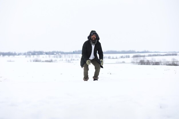 Hombre barbudo en el bosque de invierno. Atractivo joven feliz con barba a pie en el parque.