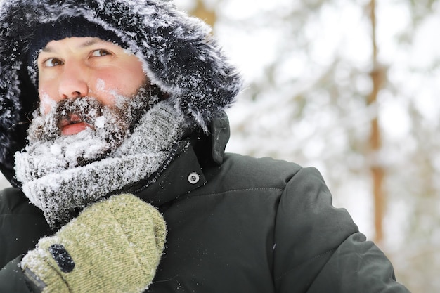 Hombre barbudo en el bosque de invierno. Atractivo joven feliz con barba a pie en el parque.