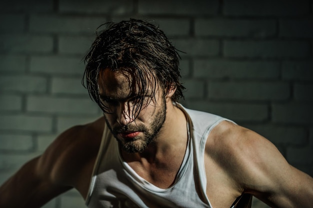 Hombre barbudo con cabello largo mojado en camiseta blanca