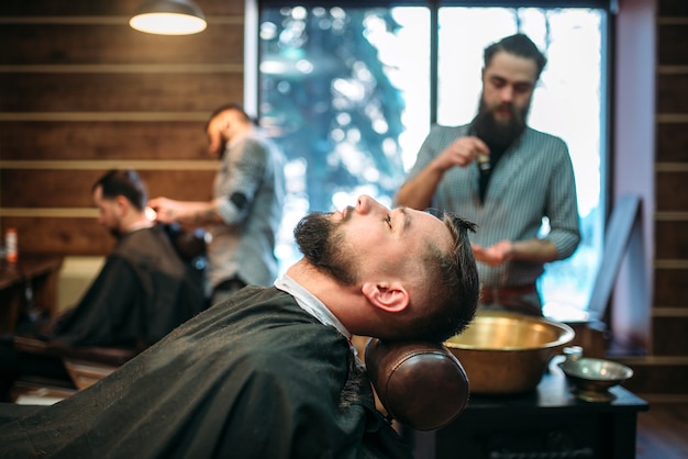 Hombre barbudo en cabo de salón en la barbería