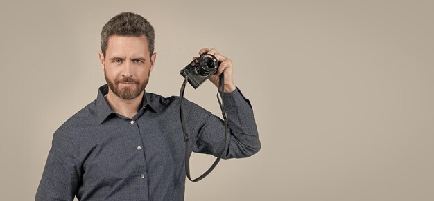 Hombre barbudo en camisa casual sostenga cámara de película fotografía analógica de fondo gris