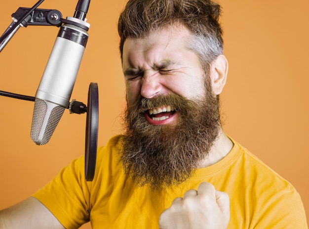 El hombre barbudo canta en el micrófono de condensador en el estudio de grabación emocional vocalista profesional masculino