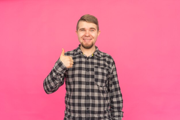 Hombre barbudo caucásico feliz con el pulgar hacia arriba en rosa