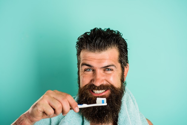 Hombre barbudo cepillarse los dientes. Cepillo de dientes. Pasta dental. Tratamientos matutinos. Rutina de la mañana. Cuidado de la salud. Higiene dental.