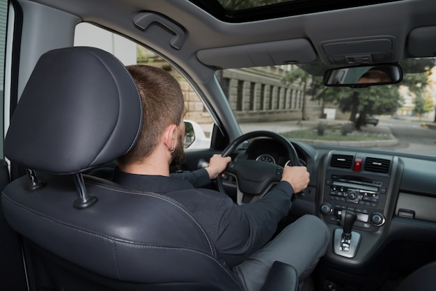 Hombre barbudo conduciendo un automóvil.