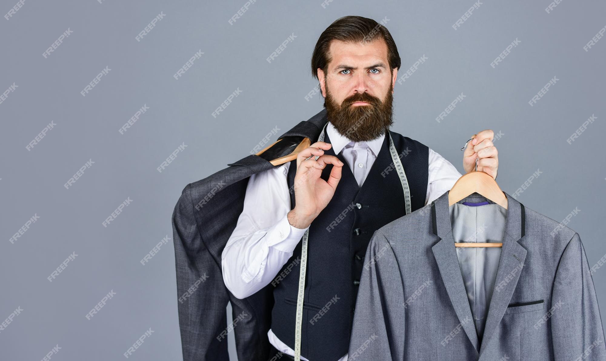 Hombre barbudo confeccionando ropa formal y vestuario de oficina empresario seguro sastre diseñando chaqueta masculina guapo sartor con cinta métrica belleza masculina y espacio de copia de moda | Foto