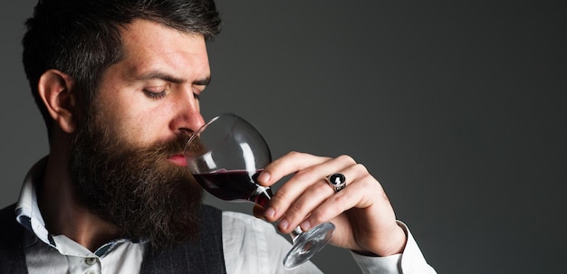 Hombre barbudo con copa de vino tinto degustación de alcohol sommelier degustador bodega enólogo masculino
